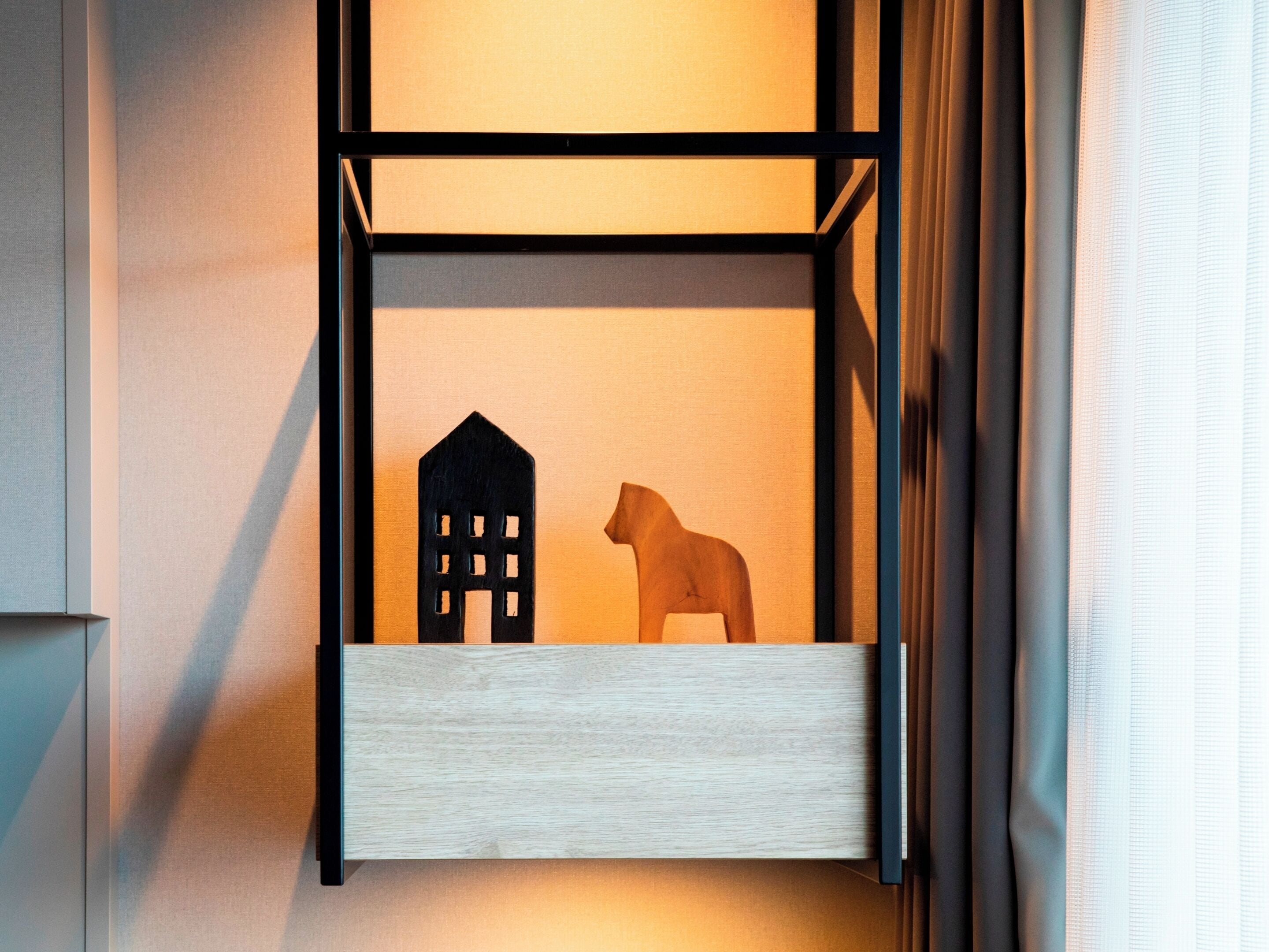 A wall-mounted shelf with a wooden house and dog figurine.