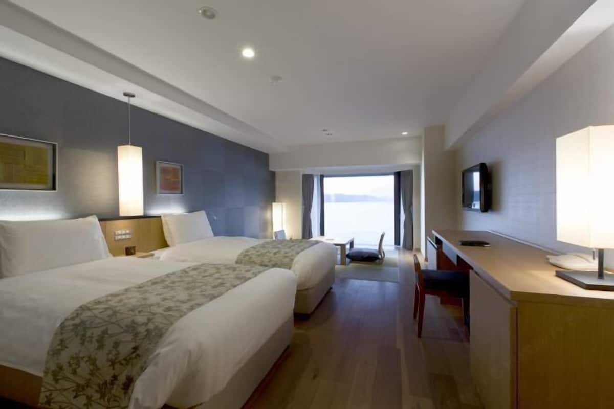 Une chambre d’hôtel avec deux lits, un bureau, une télévision et une vue sur l’extérieur.