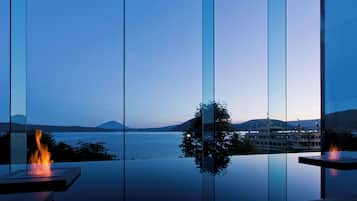 A modern interior with a large glass window offering a view of a body of water and distant mountains.