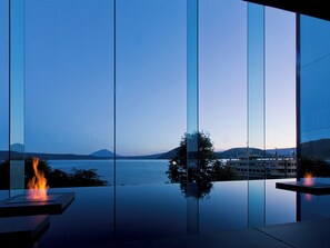 A modern interior with a large glass window offering a view of a body of water and distant mountains. - The Lake View Toya Nonokaze Resort (Toyako)