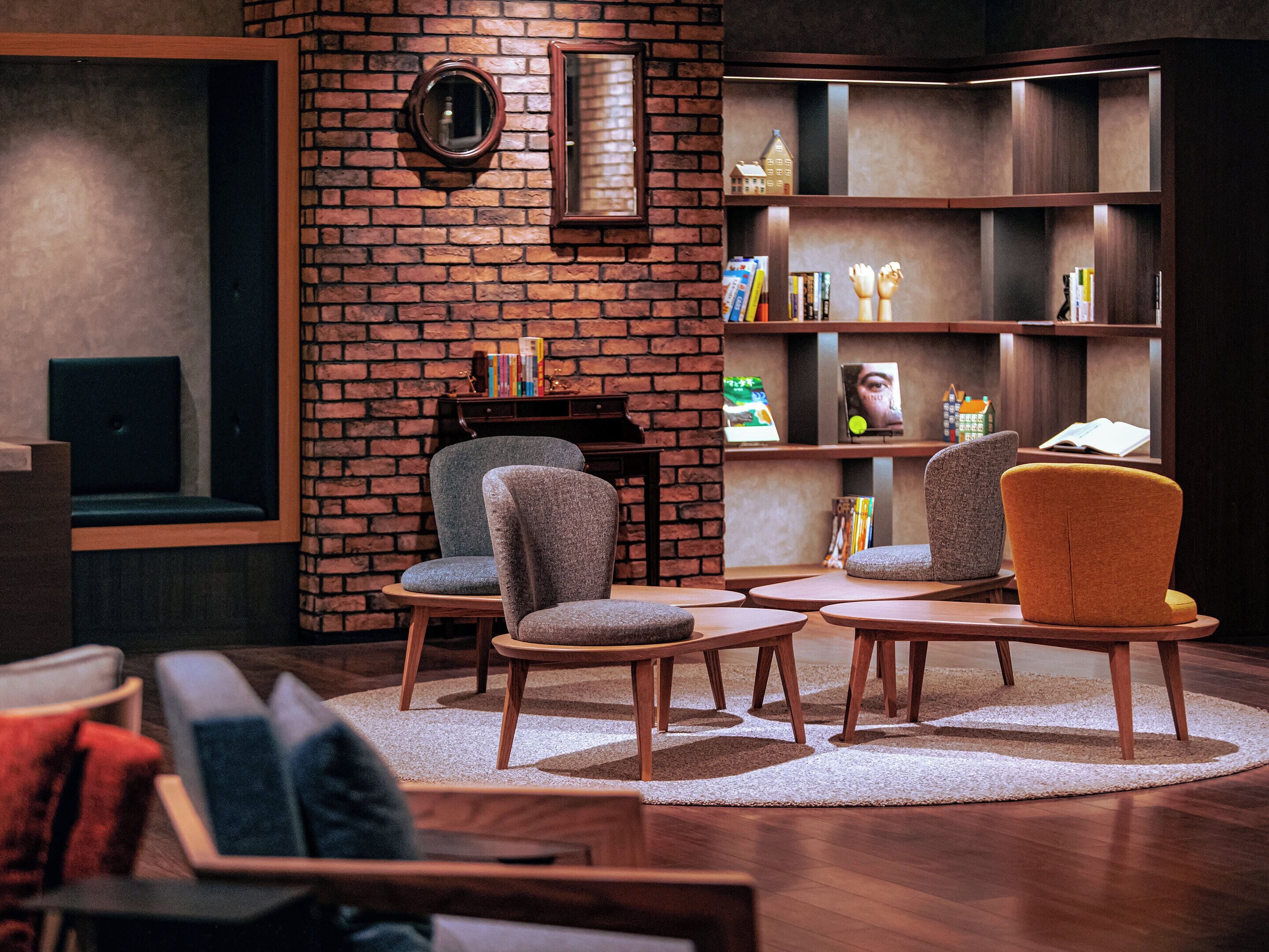 A cozy reading area with a brick wall, a piano, and a bookshelf.