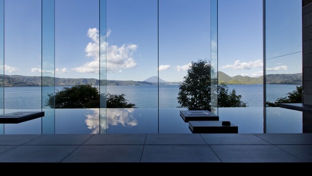 A modern interior with large glass windows offering a view of a lake and distant mountains. - The Lake View Toya Nonokaze Resort (Toyako)