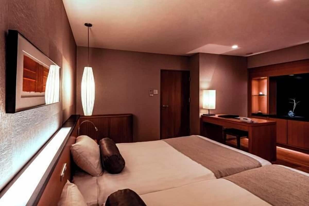 Une chambre d’hôtel avec un lit, une table de chevet, une lampe et un miroir.