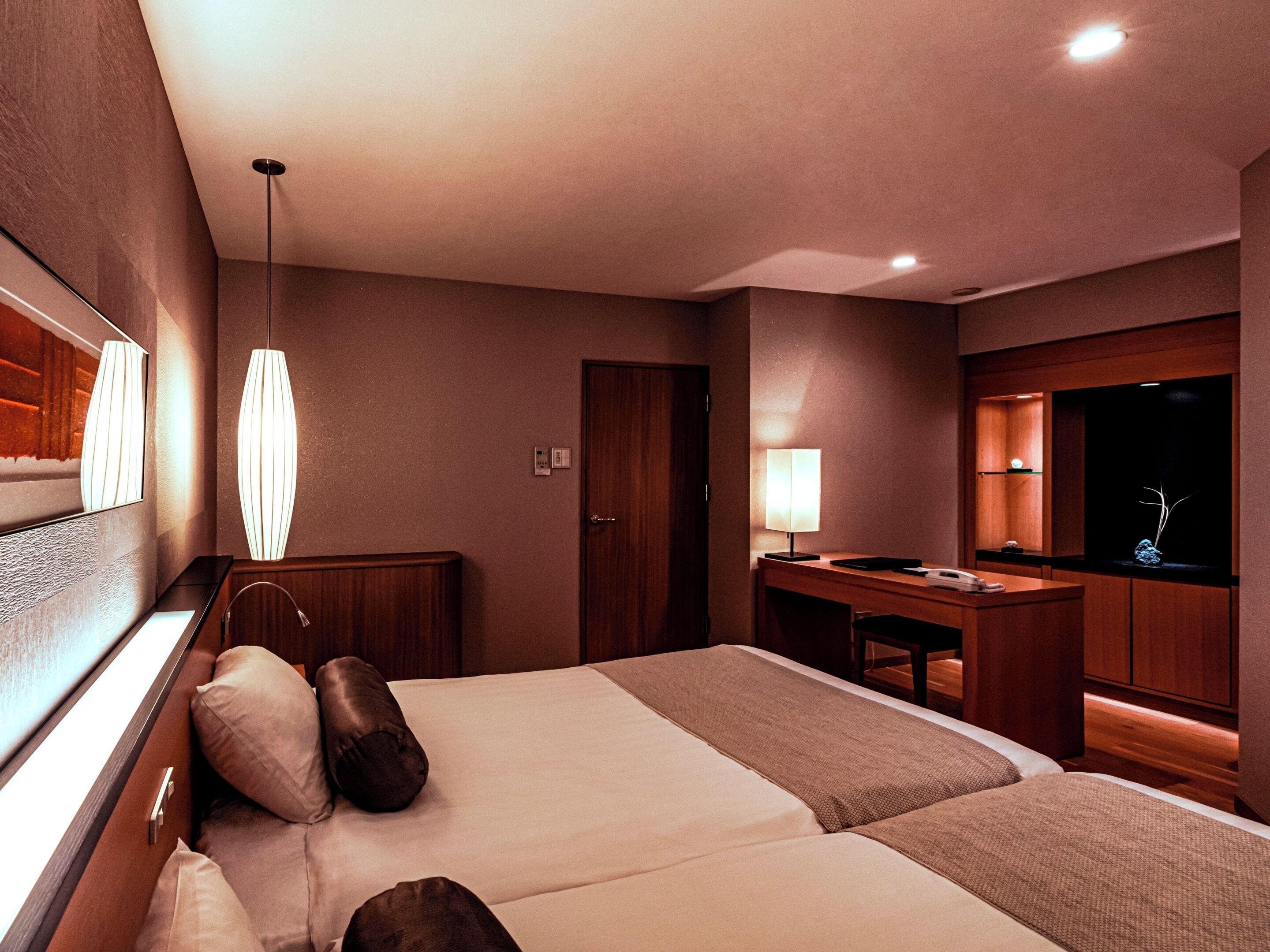 A hotel room with a large bed, a desk, a mirror, and a TV.