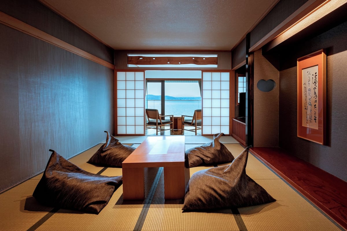 Une pièce de style japonais traditionnel, avec un sol recouvert de tatamis, une table basse et des coussins.