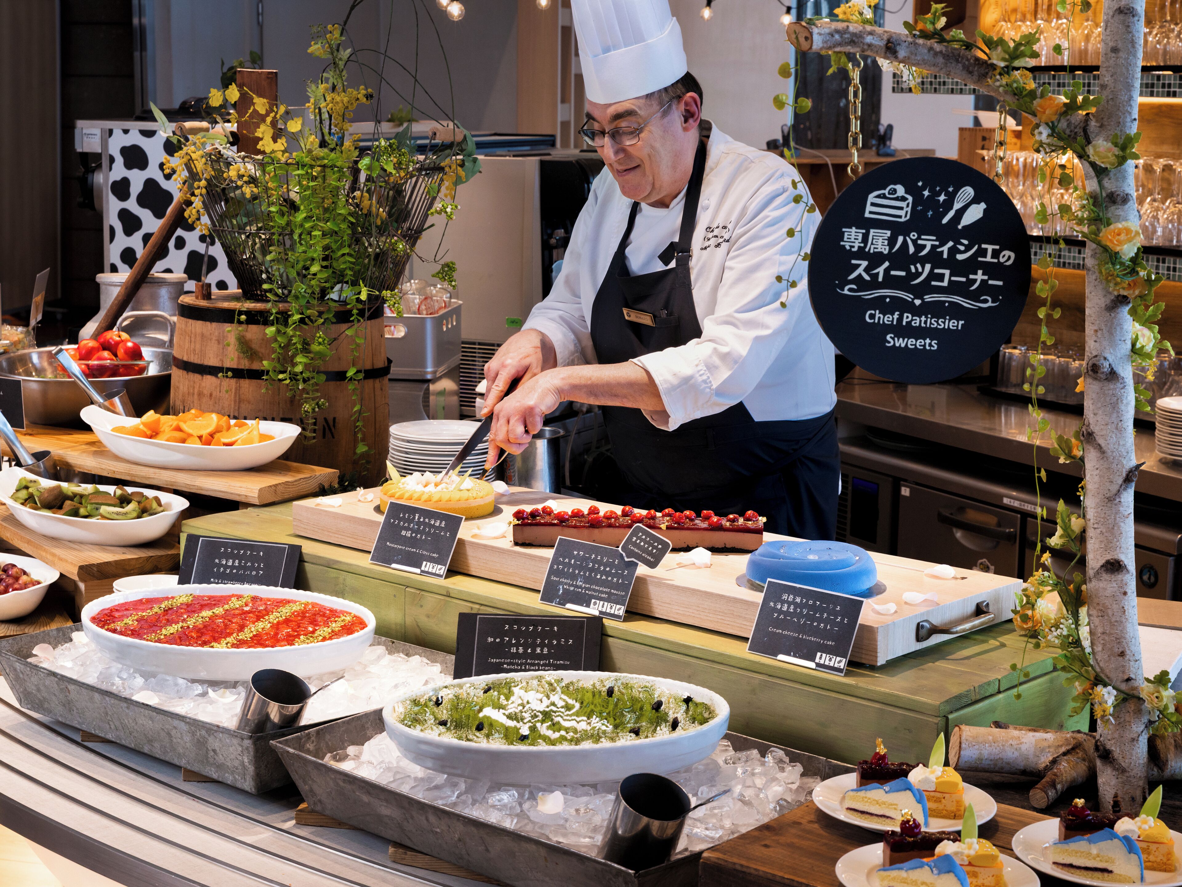 A buffet with various dishes, a chef preparing food, and a sign indicating the type of cuisine.