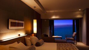 A hotel room with a large bed, a sitting area with a view of the sea, and a small table. - The Lake View Toya Nonokaze Resort (Toyako)