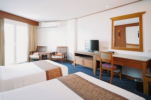 A hotel room with two beds, a desk with a television, a chair, and a large mirror on the wall. - Royal Twins Palace Hotel (Pattaya)