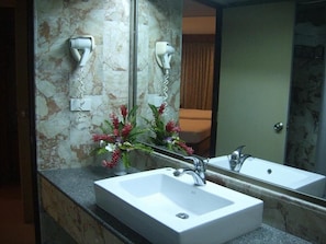 A bathroom with a white sink, a mirror, and two hair dryers mounted on the wall. - Royal Twins Palace Hotel (Pattaya)