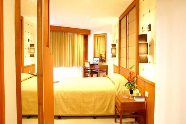 A hotel room with two beds, a desk, and a chair. - Royal Twins Palace Hotel (Pattaya)