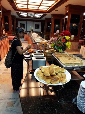 A buffet setup with various food items and a decorative floral arrangement. - Royal Twins Palace Hotel (Pattaya)