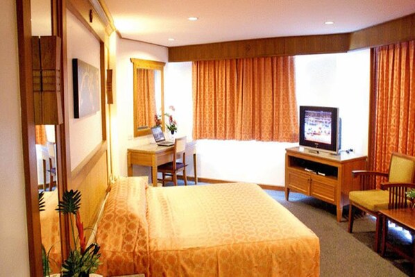 A hotel room with a bed, a desk with a computer, a television, and a chair. - Royal Twins Palace Hotel (Pattaya)