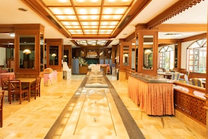 A hotel lobby with a central bar area, seating arrangements, and a decorative floor pattern.
