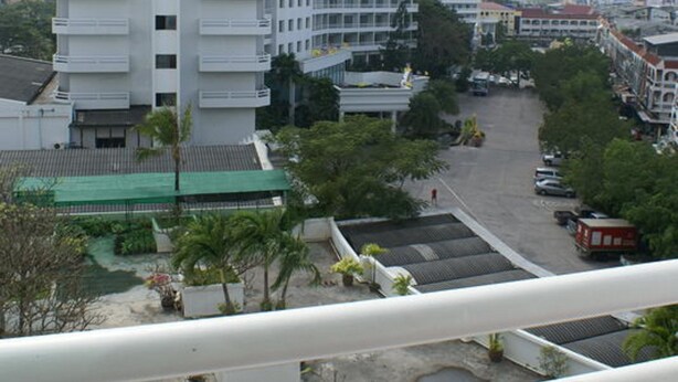 A multi-story hotel with balconies, a parking area, and a view of the surrounding cityscape. - Royal Twins Palace Hotel (Pattaya)