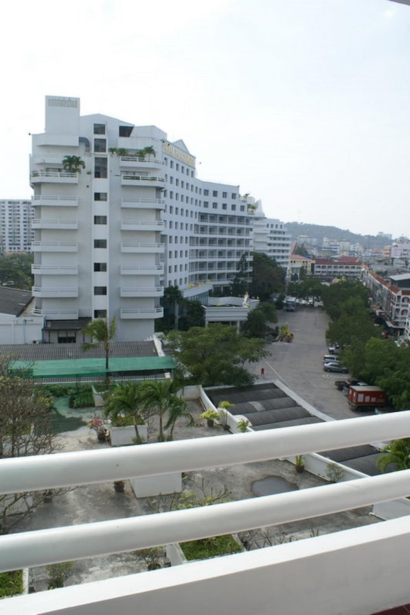 Een hotel met meerdere verdiepingen, balkons, een parkeerplaats en een uitzicht op de omliggende skyline.