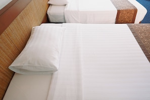 Een opgemaakt bed met witte lakens, een kussen, een houten hoofdbord en een bedovertrek met dessin.