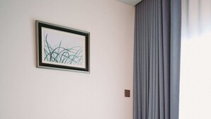 A blue sofa, a small round table, and a framed abstract artwork on the wall.