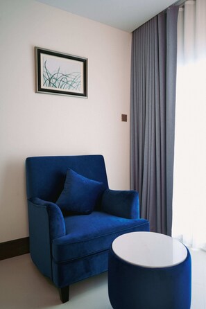 A blue sofa, a small round table, and a framed abstract artwork on the wall.