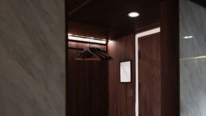 A small, enclosed room with a bench, wooden paneling, and a hanging coat rack.