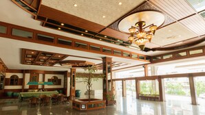 A spacious lobby with a high ceiling, a central seating area, and large windows offering a view of the outdoors. - Royal Twins Palace Hotel (Pattaya)