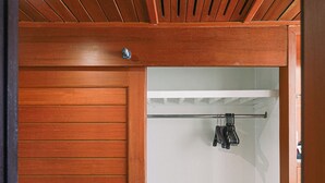 A wooden wardrobe with a sliding door, a small bedside table with drawers, and a hanging rack with clothes. - Royal Twins Palace Hotel (Pattaya)