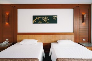 Quarto de hotel com duas camas de solteiro, cabeceira em tear, obra de arte pendurada na parede e telefone na mesinha de cabeceira.