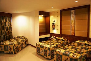A hotel room with three beds, a large mirror, and a wall-mounted shelf. - Royal Twins Palace Hotel (Pattaya)