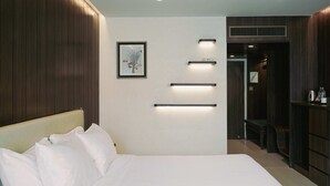 A hotel room with a bed, a framed artwork, and built-in lighting fixtures. - Royal Twins Palace Hotel (Pattaya)
