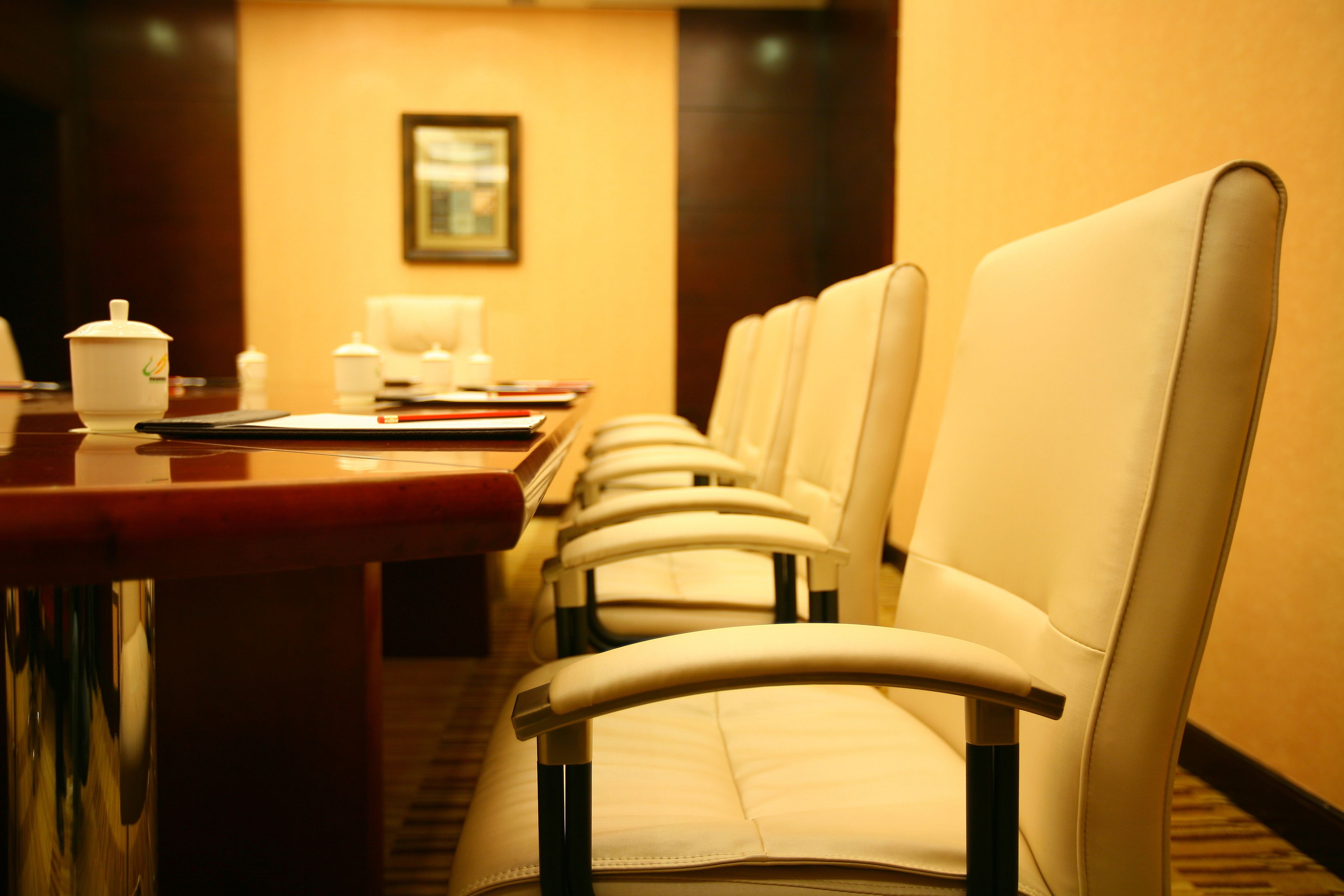 Un salón de conferencias de hotel con una larga mesa, varias sillas y una estación de café.