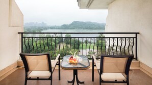 A balcony with two chairs and a table, overlooking a river and hills. - COUNTRY GARDEN Chizhou Phoenix Hotel (Chizhou)