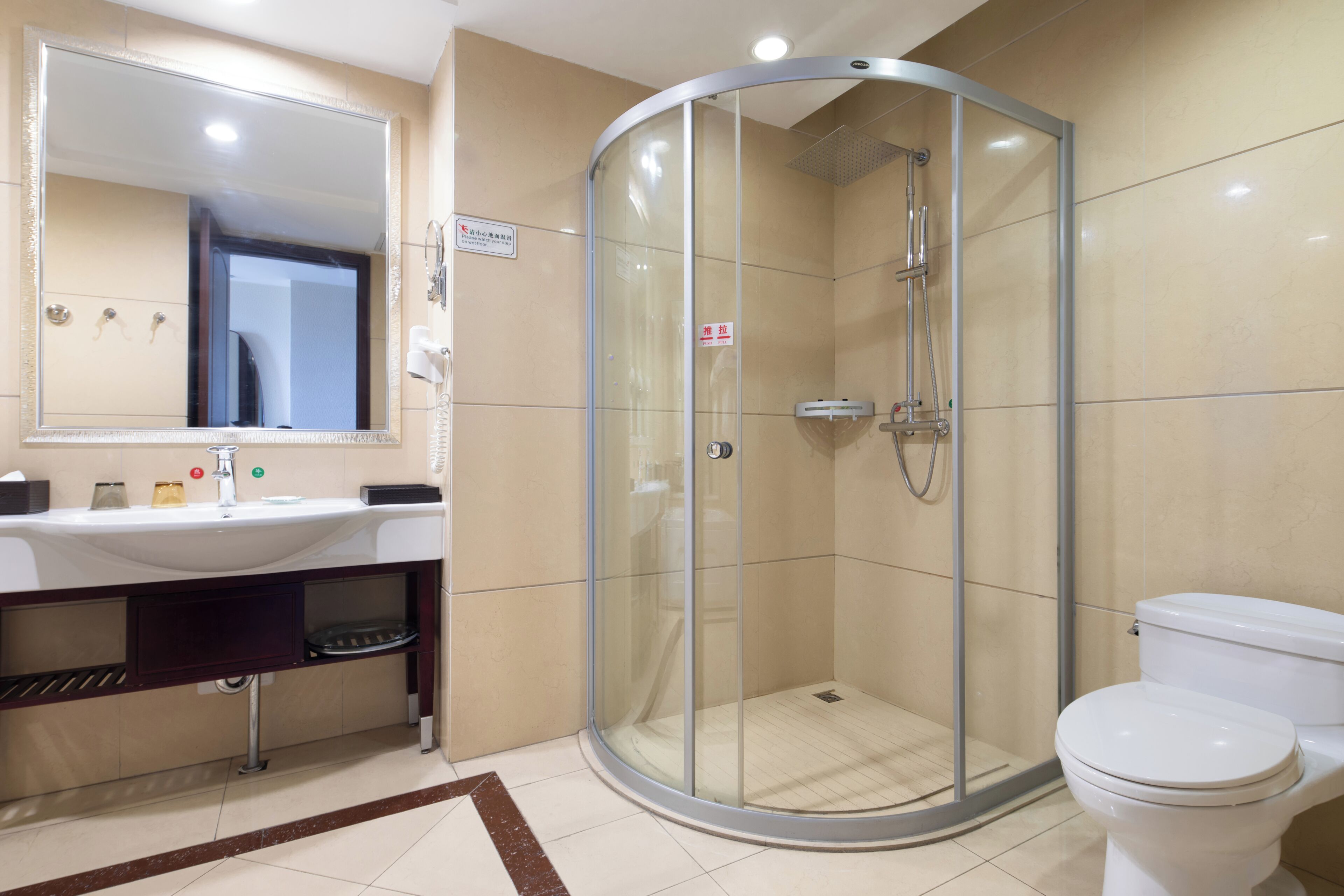 A modern bathroom with a glass-enclosed shower, a white sink, and a toilet.