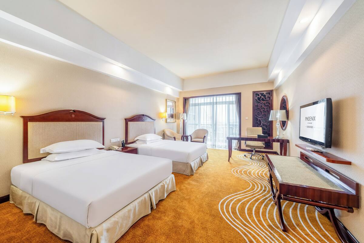 Une chambre d’hôtel avec deux lits, un bureau, une télévision et une grande fenêtre.