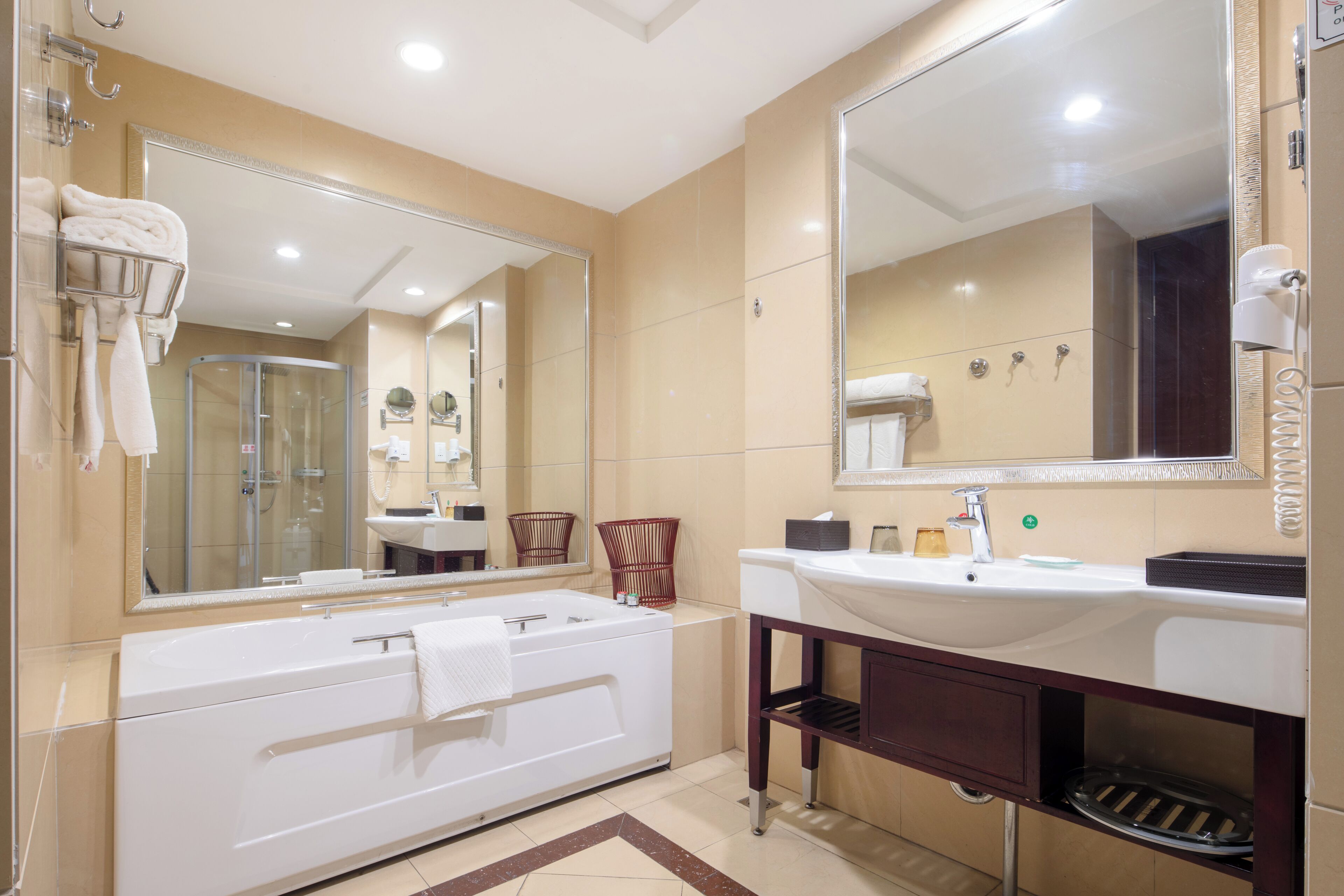 Un baño moderno con un espejo grande, una bañera, un lavabo y una ducha.
