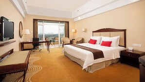 A hotel room with a bed, desk, chair, television, and a balcony with a view. - COUNTRY GARDEN Chizhou Phoenix Hotel (Chizhou)