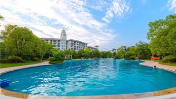 A large swimming pool with a clear view of a hotel building in the background.