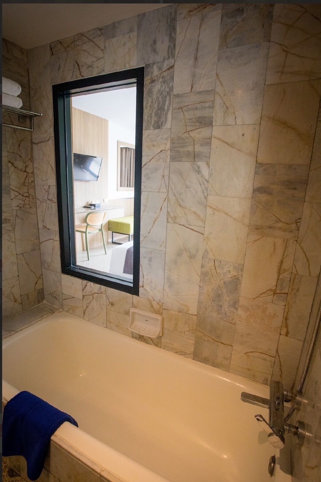 Une salle de bain avec une baignoire, une fenêtre et un miroir.