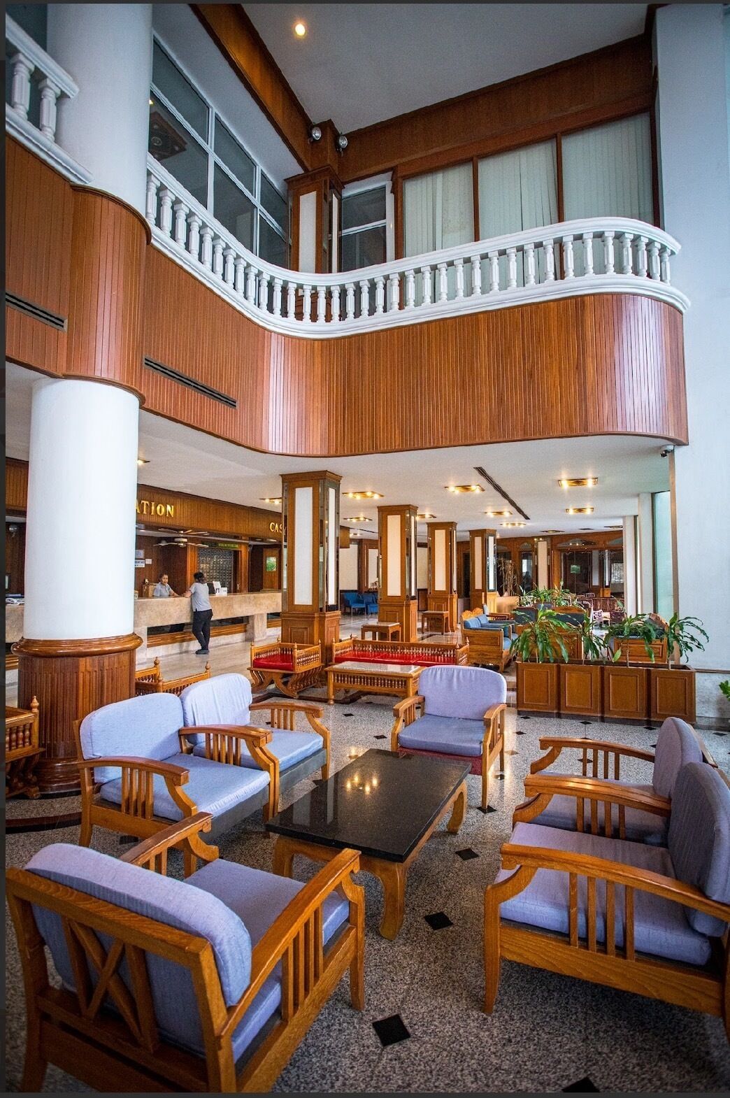 A spacious lobby with a central seating area, wooden paneling, and a reception desk.