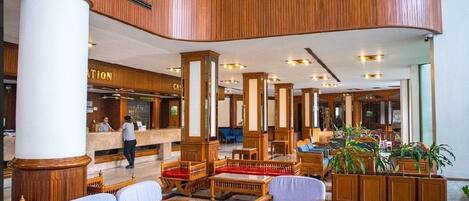 A spacious lobby with a central seating area, wooden paneling, and a reception desk.