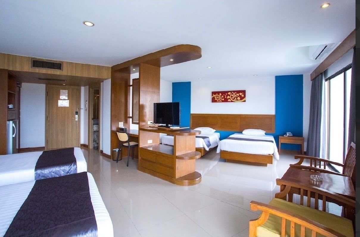 Una habitación de hotel con dos camas, un escritorio, un televisor y un área de comedor.