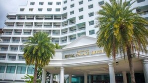 Un hôtel à plusieurs étages, doté d’une entrée imposante et d’un grand palmier en premier plan.