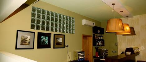 Una habitación con una zona de bar, una escalera y una pared decorada con cuadros.