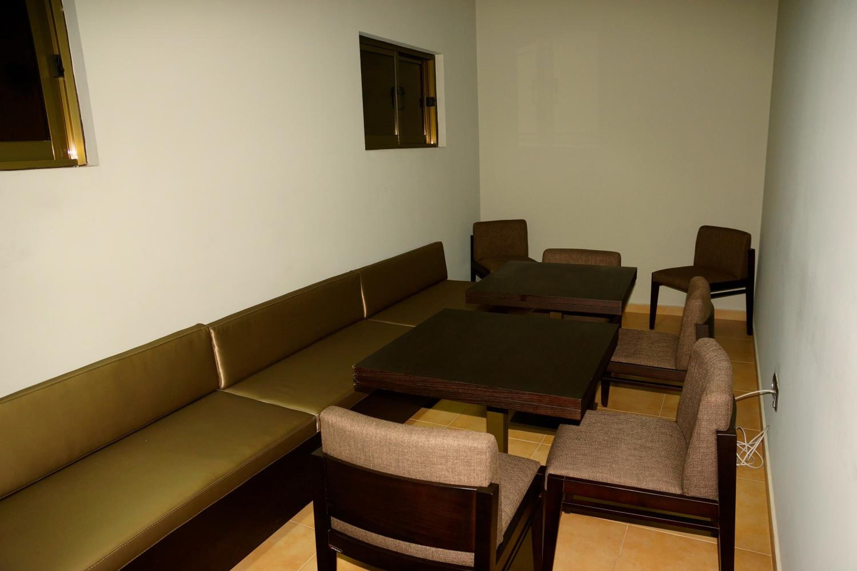 A room with a sofa, two wooden tables, and four chairs.