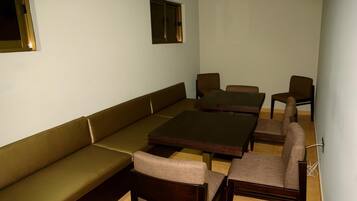 A room with a sofa, two wooden tables, and four chairs.