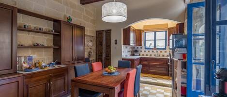 Un'ampia cucina con mobili in legno, pavimento a scacchi e lampadario.