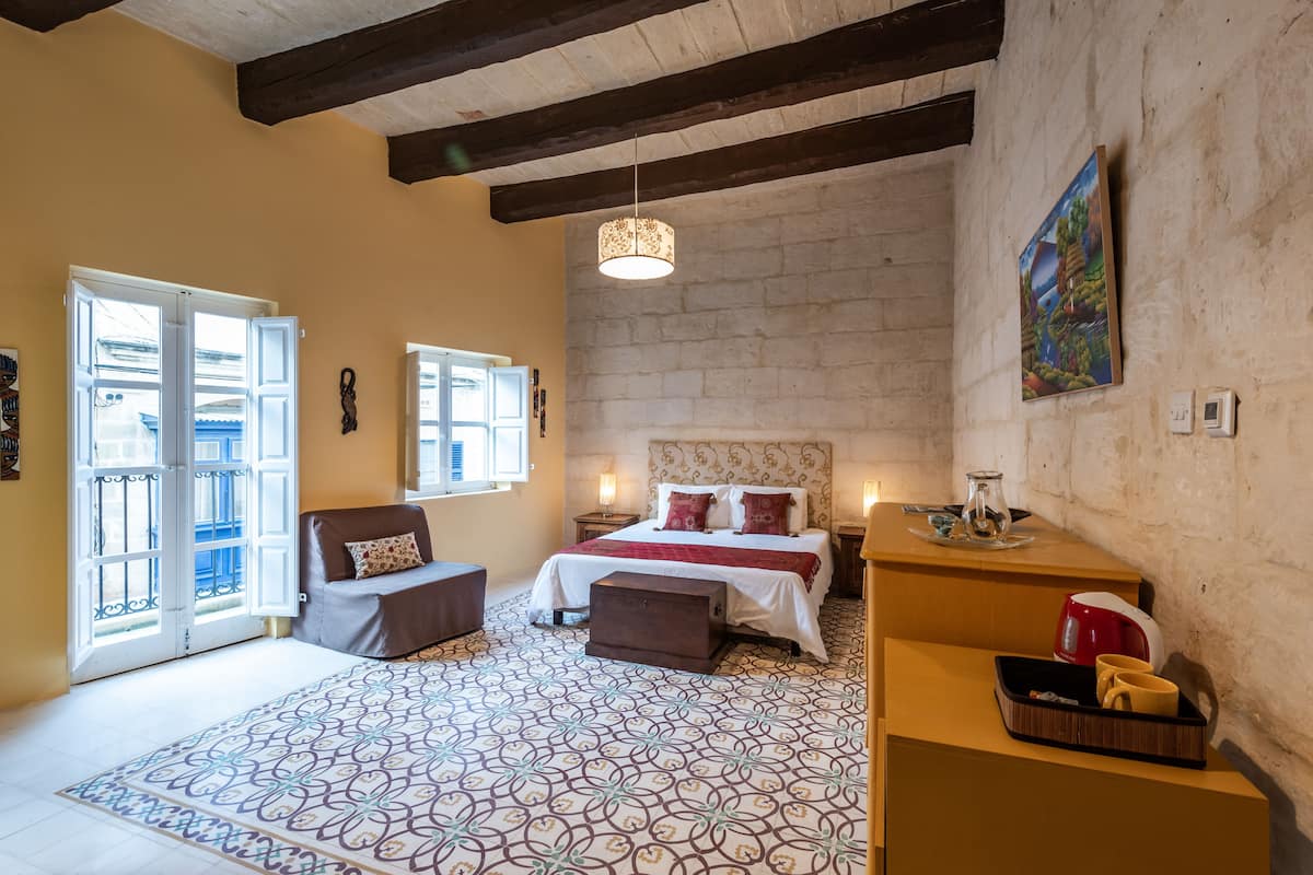A bedroom with a bed, a sofa, a coffee table, and a desk.