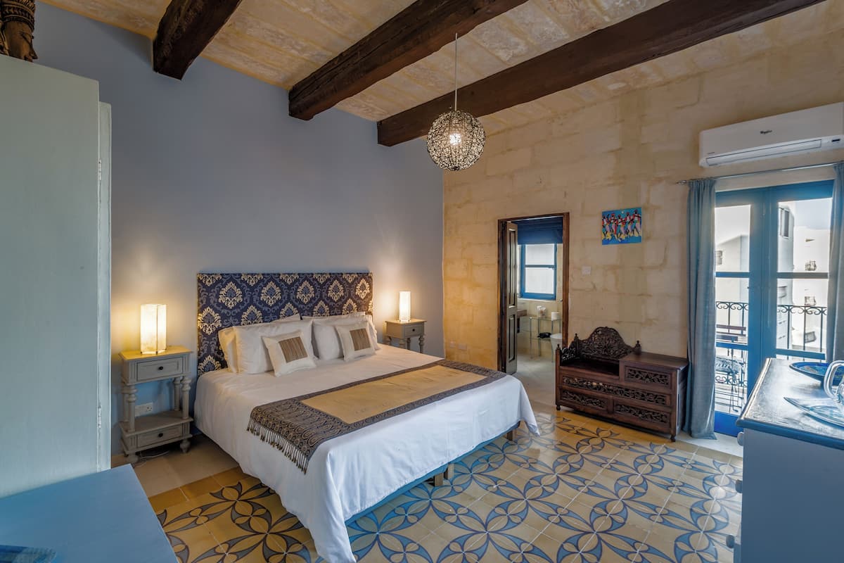 A bedroom with a large bed, bedside lamps, a dresser, and a patterned floor.