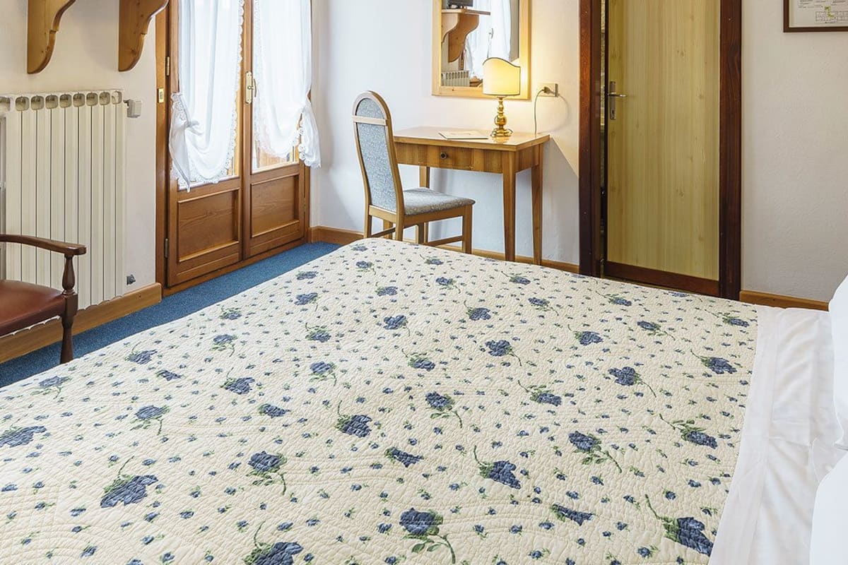 A bedroom with a bed, a chair, a desk, and a mirror.