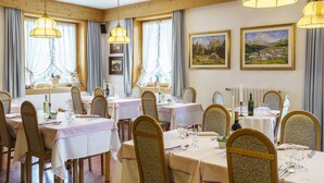 A dining area with multiple tables set for guests, featuring wooden chairs and a classic interior design.