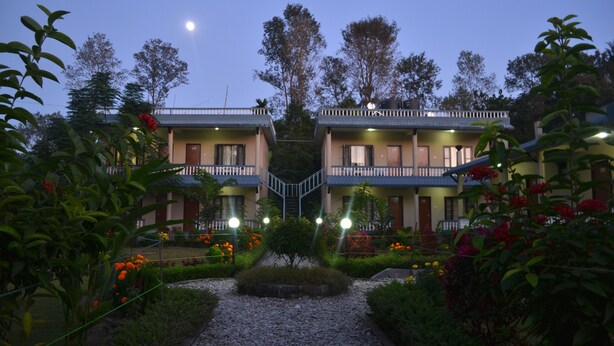 A hotel with two-story buildings, a central staircase, and a garden with gravel paths and flowering plants.