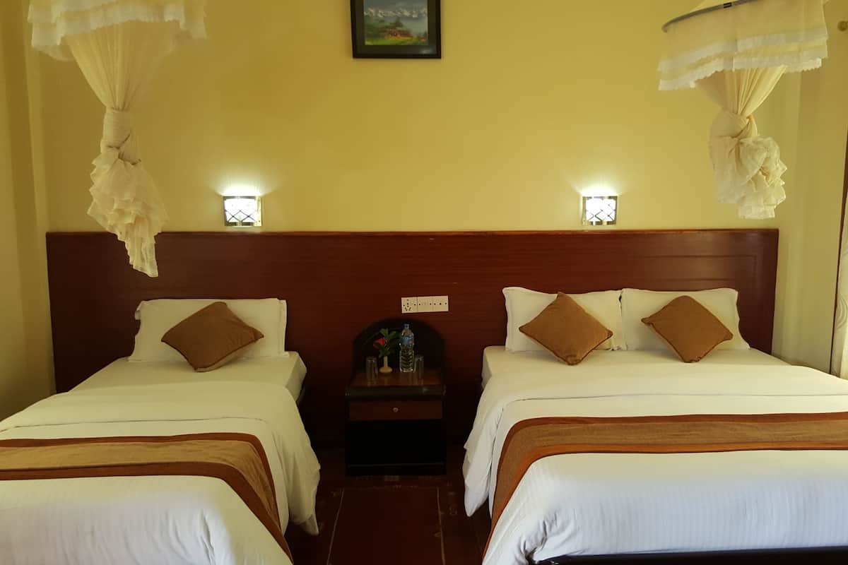 A hotel room with two beds, a nightstand, a small table, and a wall-mounted picture.